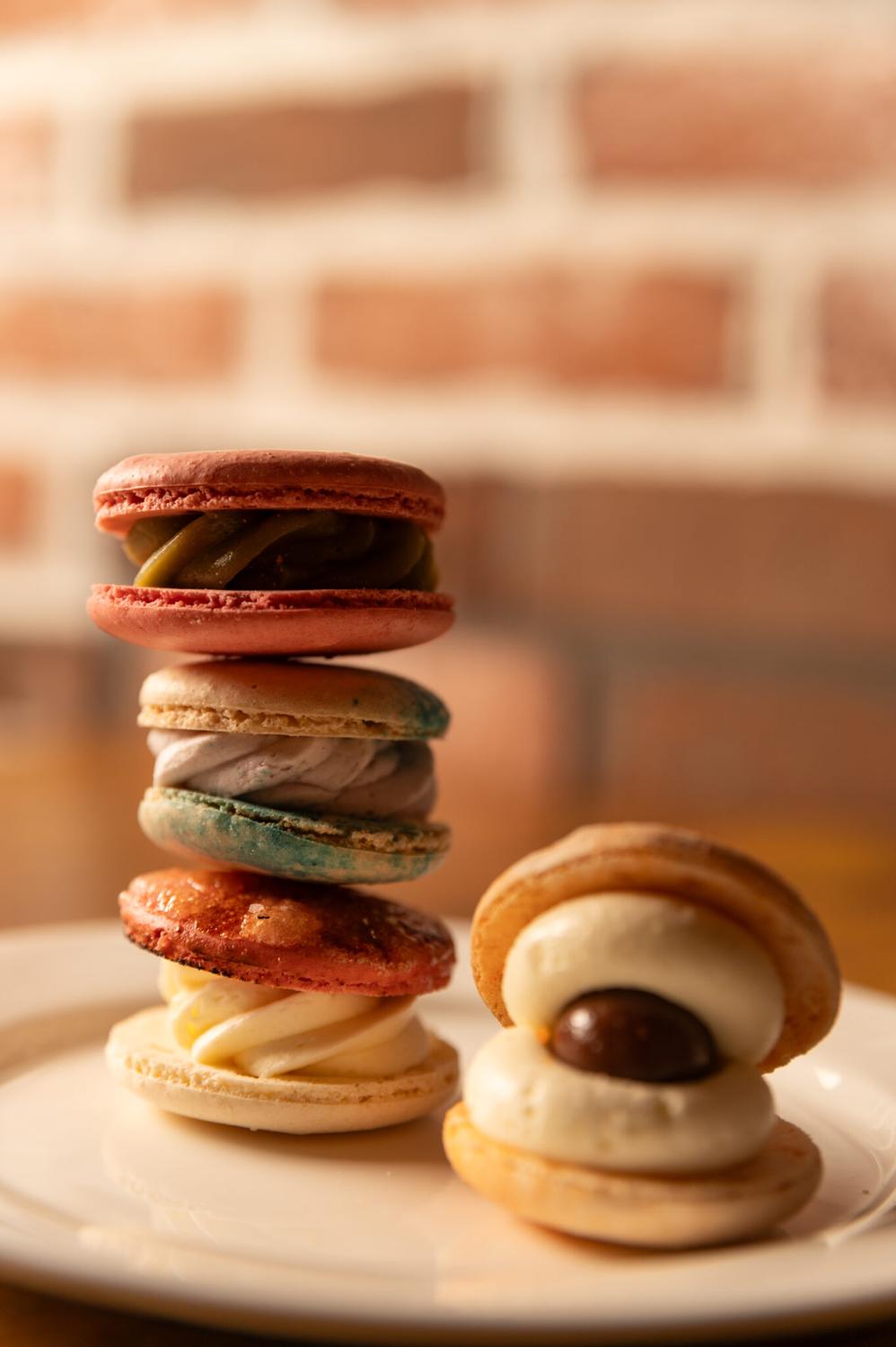 A stack of macarons beside a plate of filled macarons